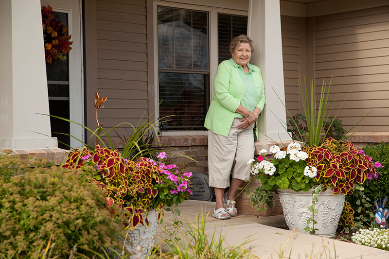 The Oaks at Bartlett | Resident standing outside of landscaped cottage home