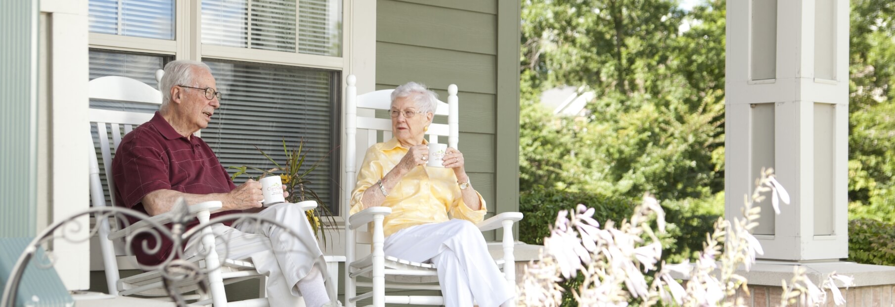 The Oaks at Bartlett | Senior couple having coffee on the porch, while sitting in rocking chairs